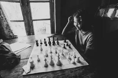 a girl sits in front of a chessboard, smiling